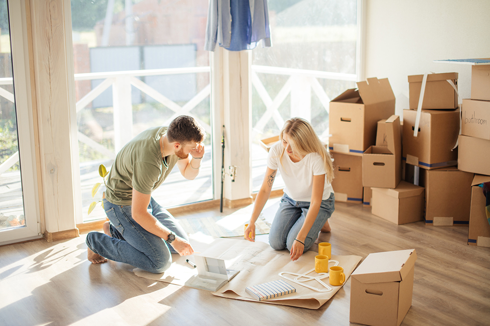 Young couple looking blueprints of they new house. Planning interior design